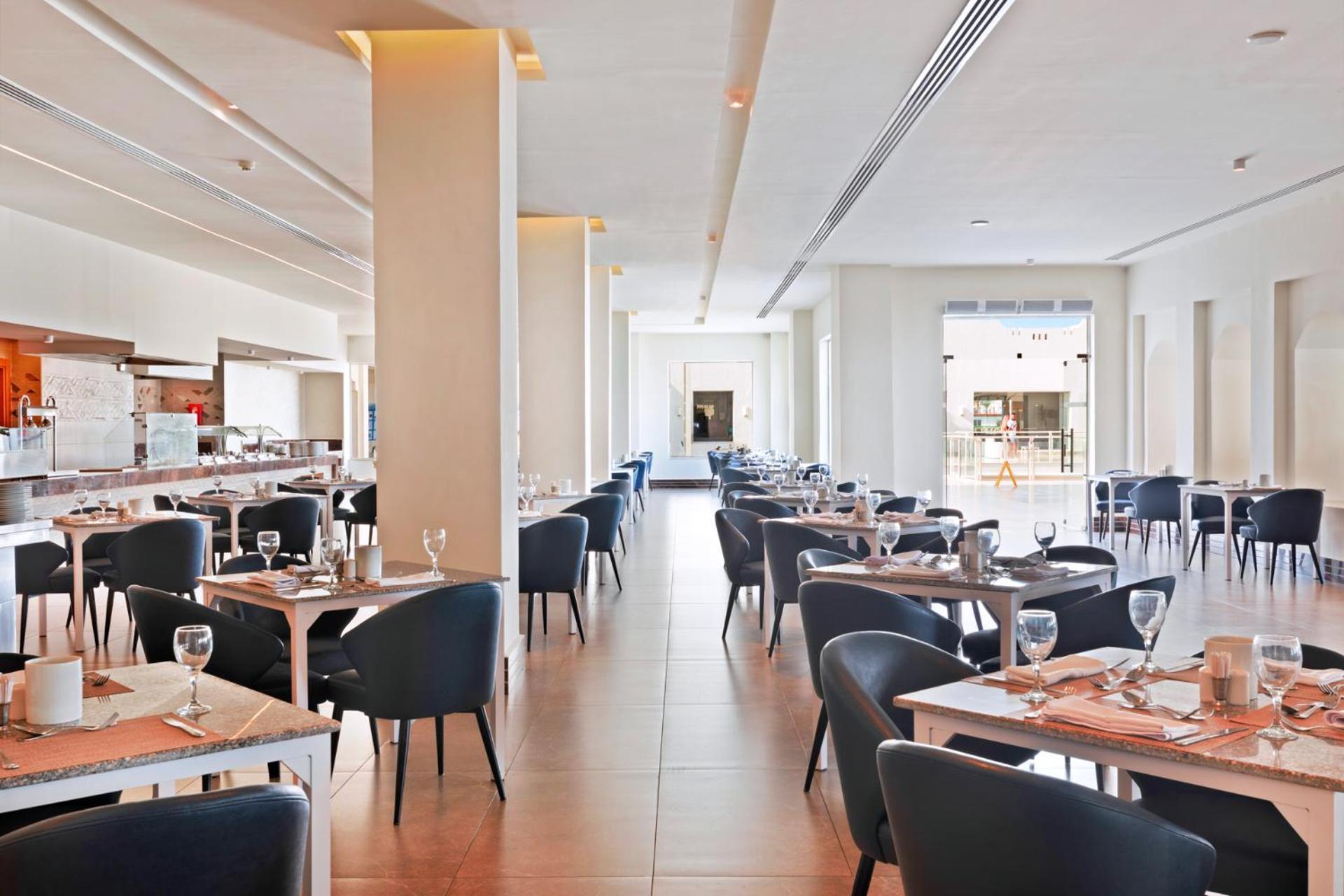 Pickalbatros Royal Grand Sharm - Adults Friendly 16 Years Plus Exteriér fotografie The photo shows the interior of a modern restaurant. The space is bright and airy, featuring large windows that allow natural light to flood in. There are several tables arranged throughout the room, each covered with placemats and set with glasses a