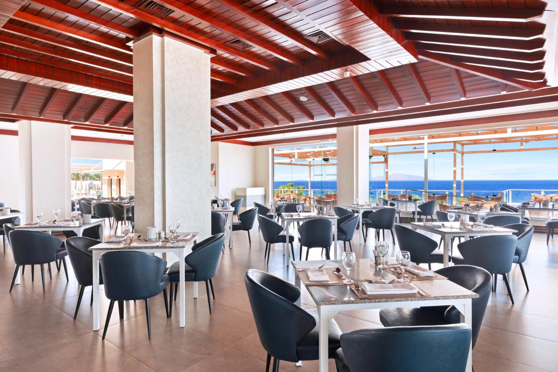 Pickalbatros Royal Grand Sharm - Adults Friendly 16 Years Plus Exteriér fotografie The photo shows a modern restaurant interior with a spacious and well-lit design. There are several tables set for dining, featuring white tablecloths and elegant dinnerware. The chairs are sleek and dark, contrasting with the bright surroundings. La