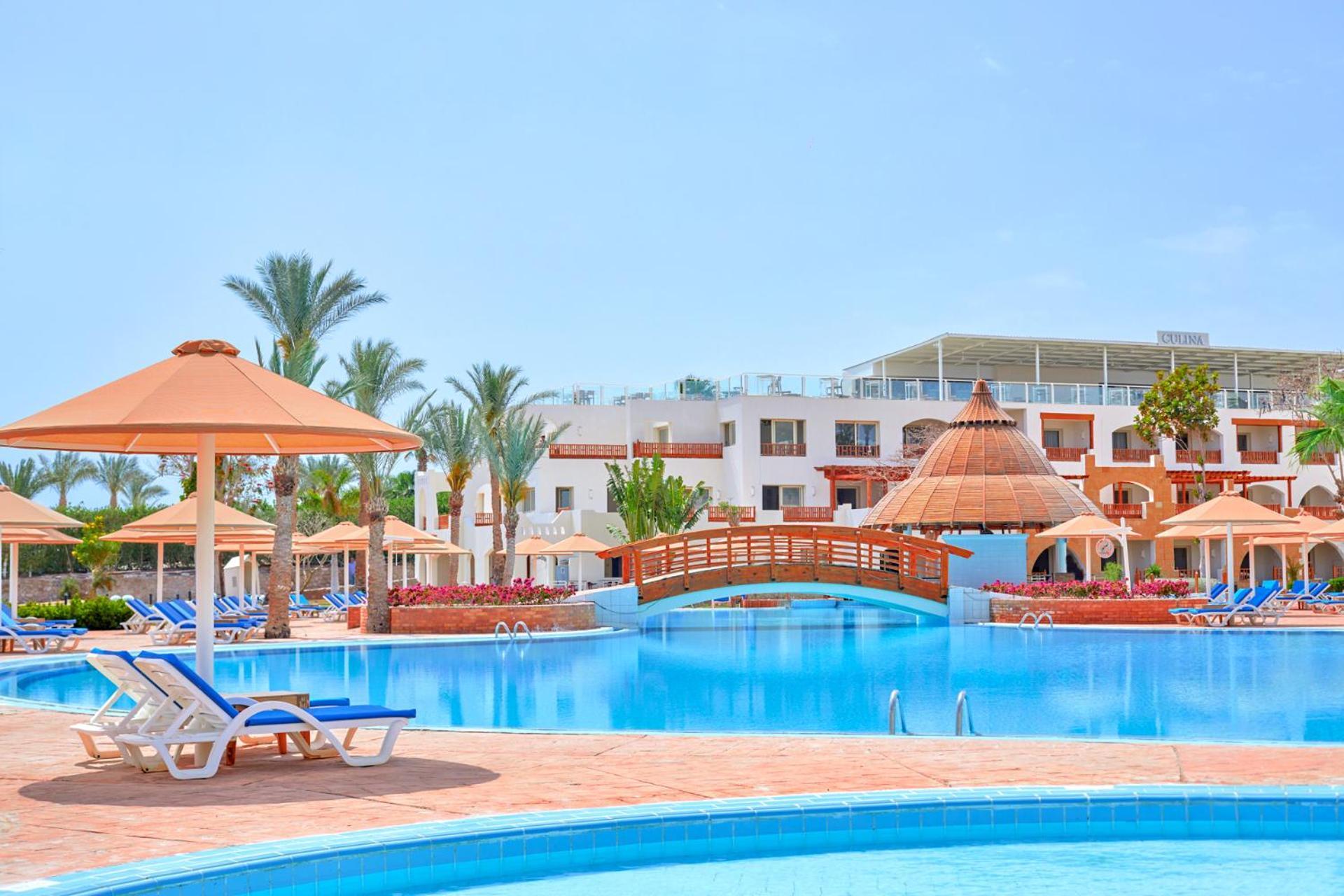 Pickalbatros Royal Grand Sharm - Adults Friendly 16 Years Plus Exteriér fotografie The photo depicts a beautiful resort setting featuring a large, inviting swimming pool. There are several lounge chairs positioned around the pool, along with straw umbrellas providing shade. In the background, there is a charming wooden bridge archi