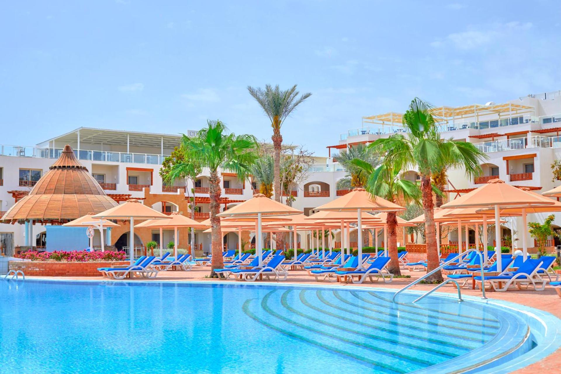 Pickalbatros Royal Grand Sharm - Adults Friendly 16 Years Plus Exteriér fotografie The photo depicts a resort scene featuring a beautiful swimming pool with clear blue water. Surrounding the pool are several lounge chairs arranged under large umbrellas, providing shade. In the background, there are palm trees that enhance the tropi